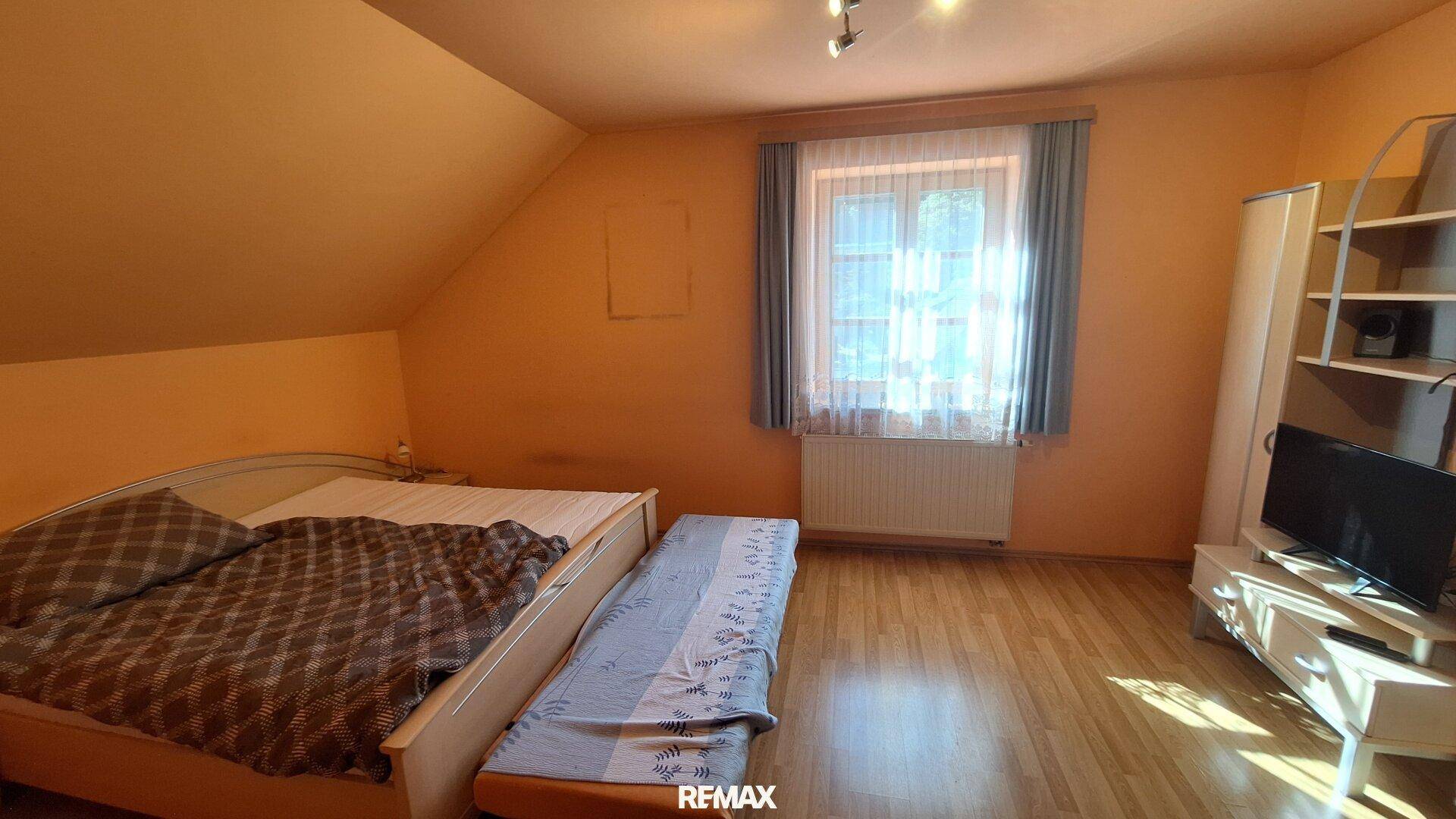 Schlafzimmer im Dachgeschoss mit Holzboden, Doppelbett und Dachschräge.