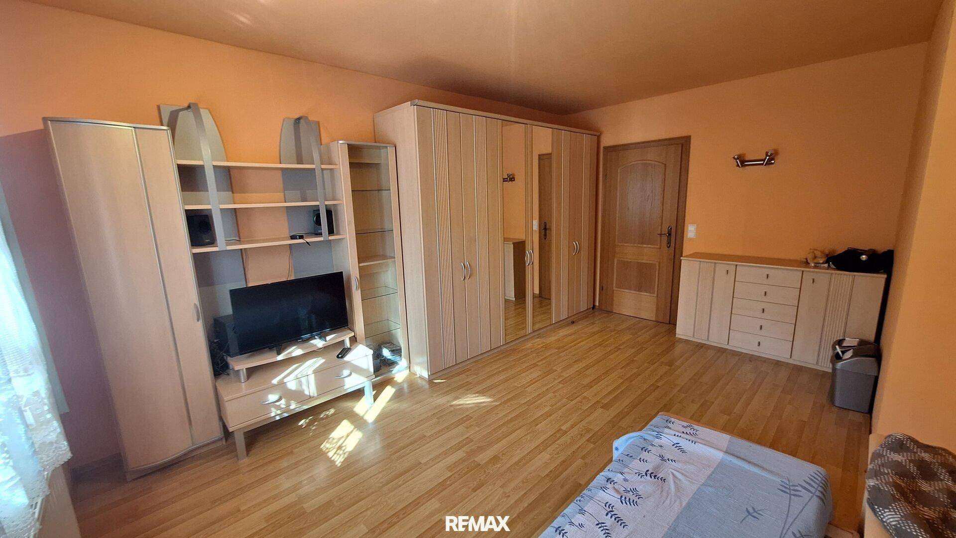 Geräumiges Schlafzimmer mit Holzboden, Kleiderschränken und viel Tageslicht.
