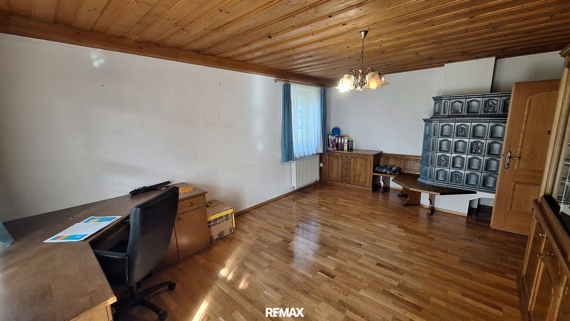 Wohnzimmer mit Holzboden, Kachelofen und traditioneller Einrichtung, ideal für gemütliche Abende.