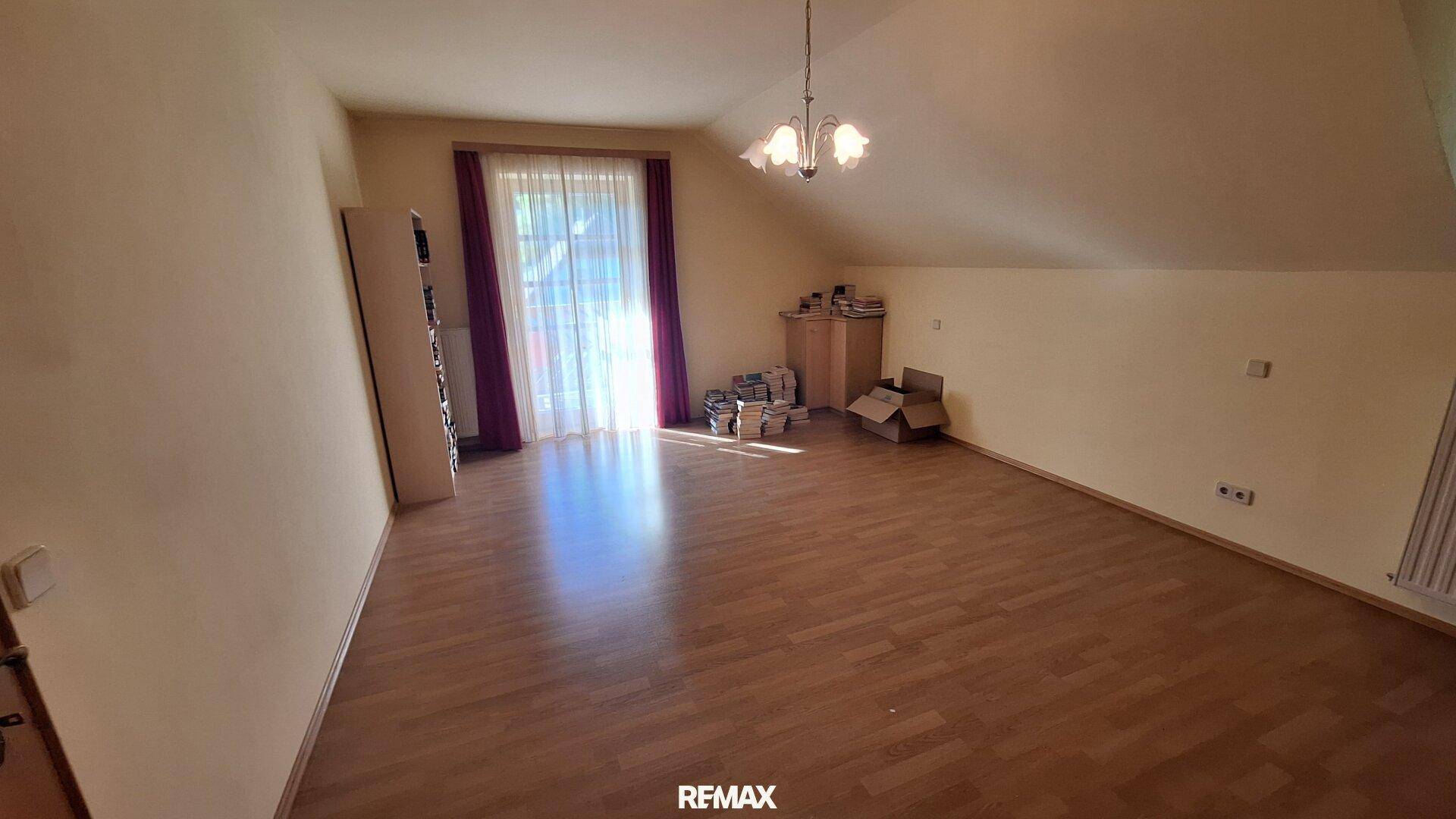 Geräumiges Zimmer im Dachgeschoss mit Holzboden und viel Tageslicht durch die Fenster.