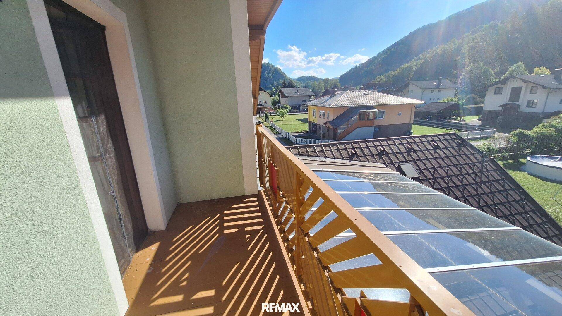Überdachter Balkon mit Holzgeländer und Blick auf die umliegende Berglandschaft.