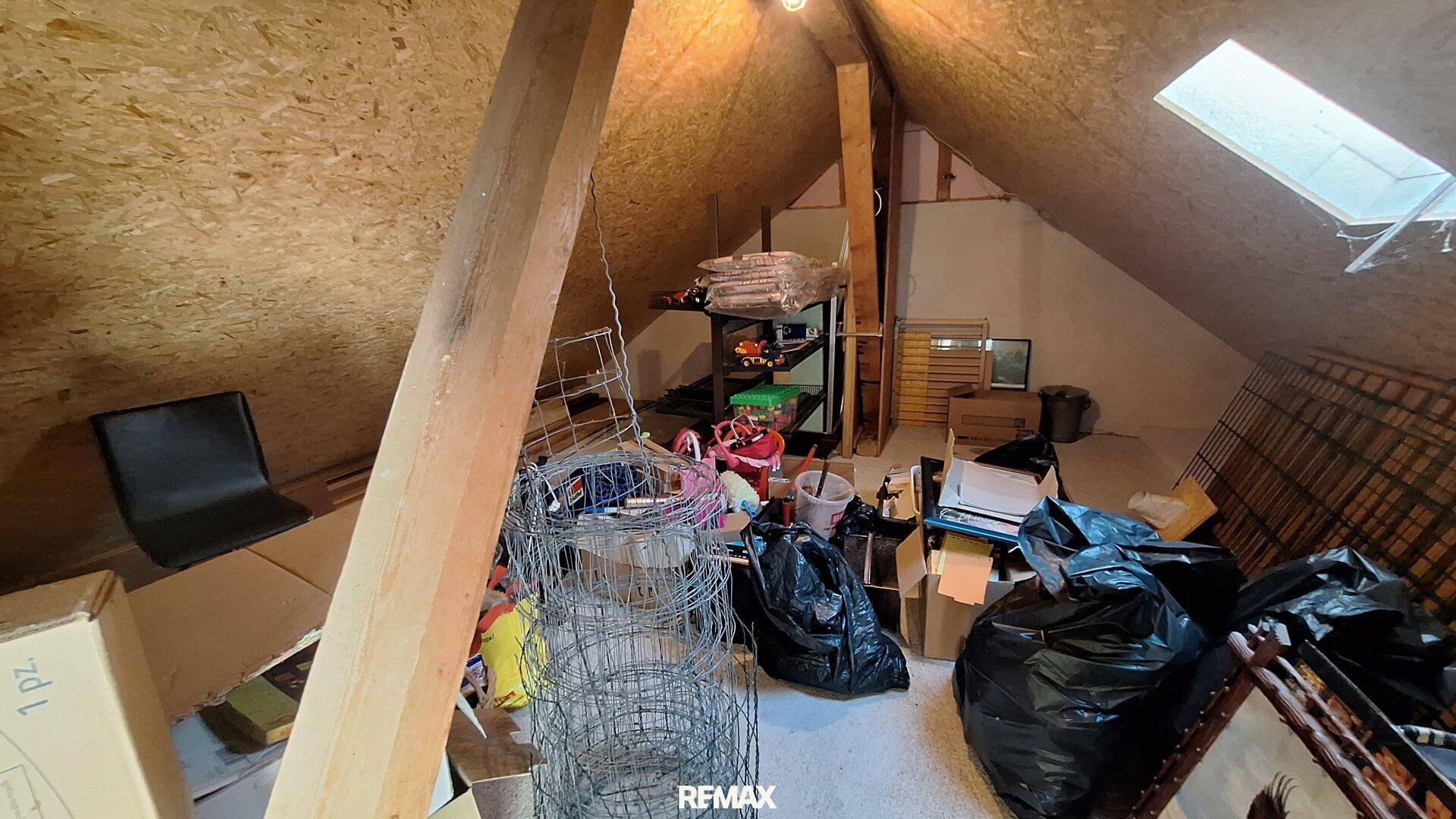 Unausgebauter Dachboden mit Holzbalken, Dachfenster und Stauraum.