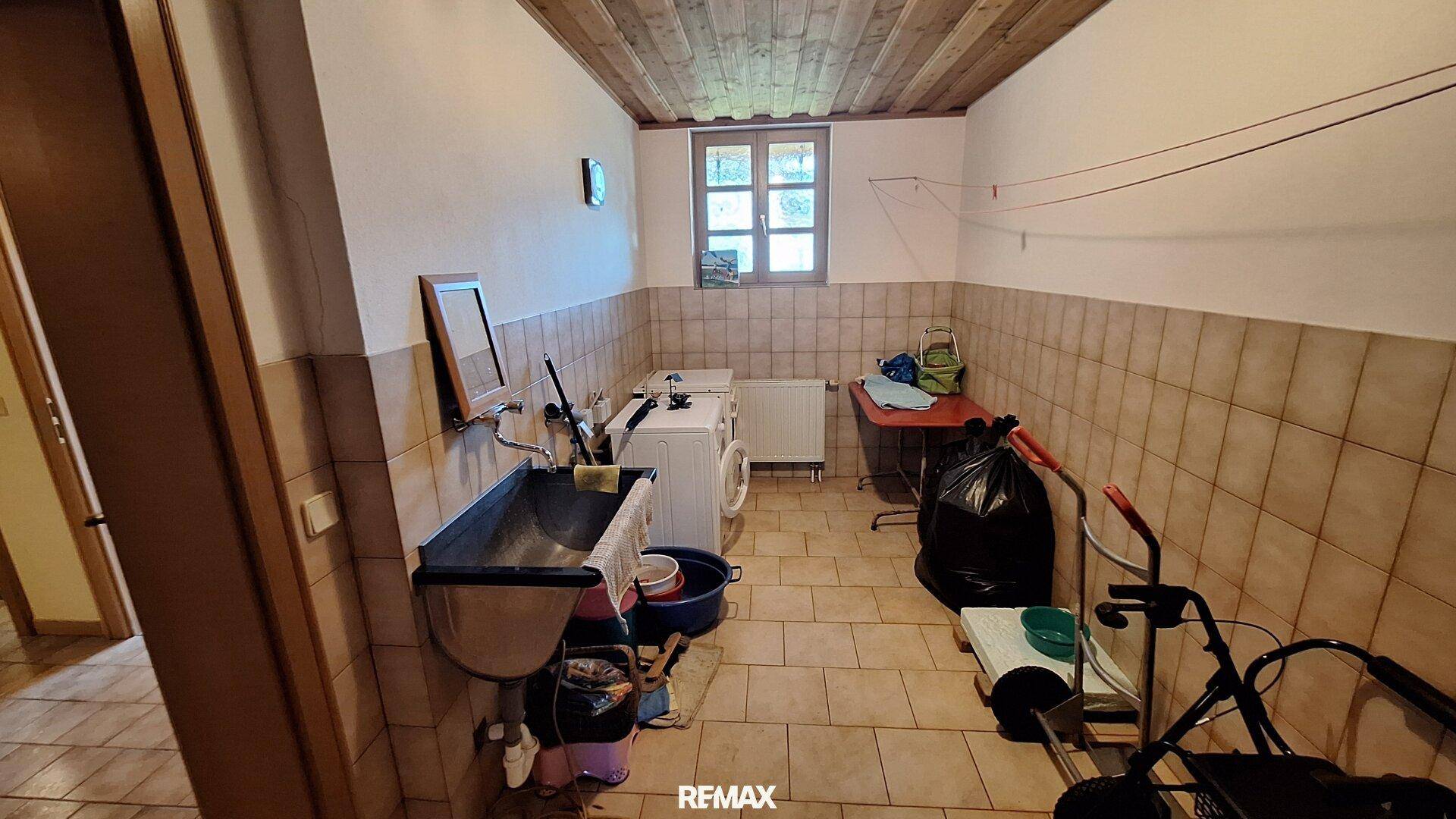 Waschküche mit Waschbecken, Waschmaschine und Trockner, ideal für den Haushalt.