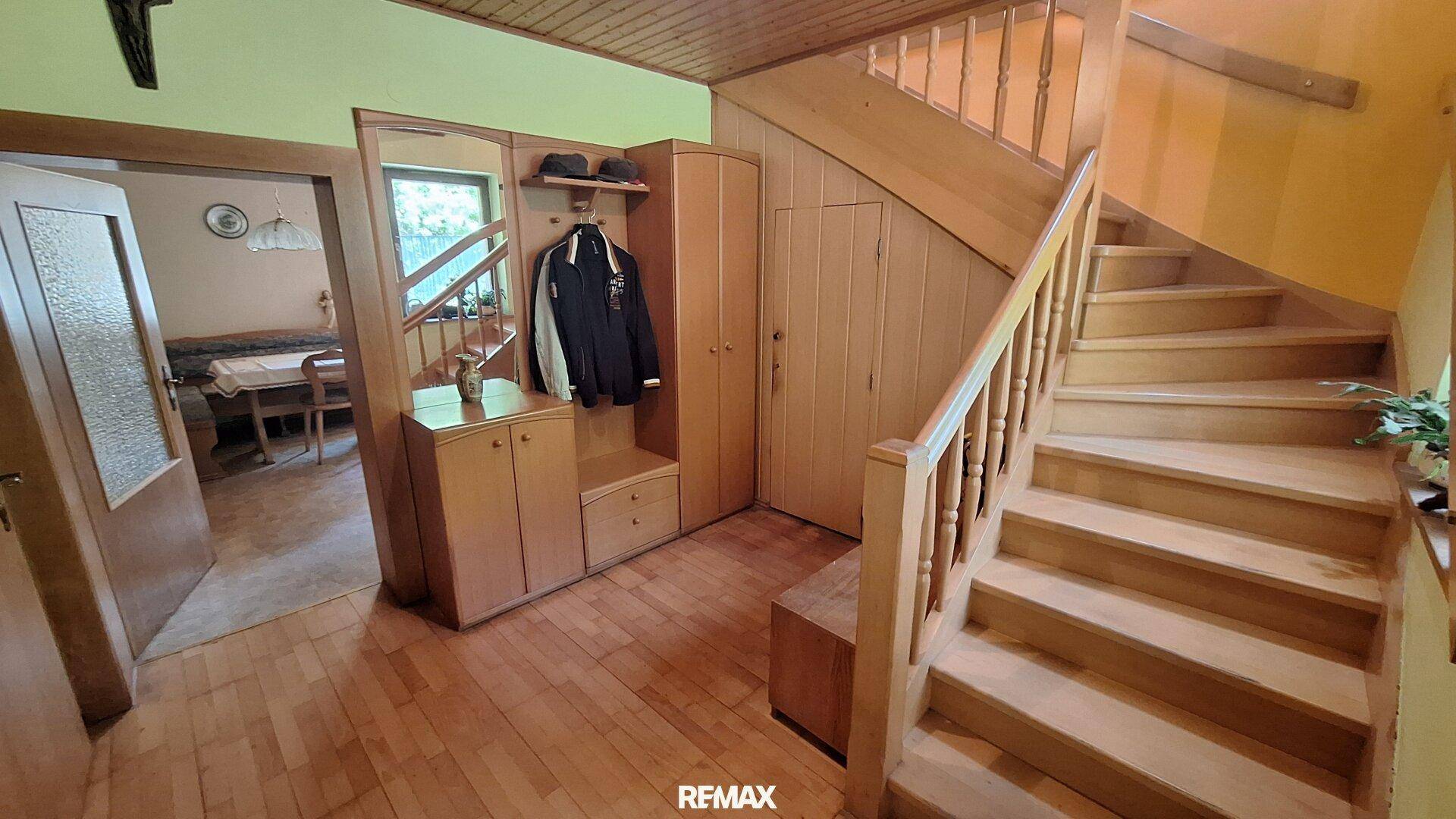 Heller Eingangsbereich mit Holztreppe, Garderobe und Zugang zu weiteren Räumen.