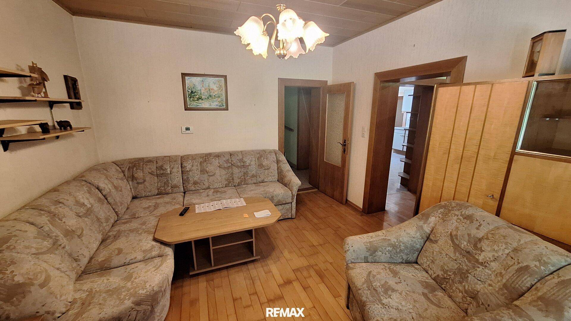 Wohnzimmer mit bequemer Eckcouch, Holzboden und traditioneller Deckenverkleidung.