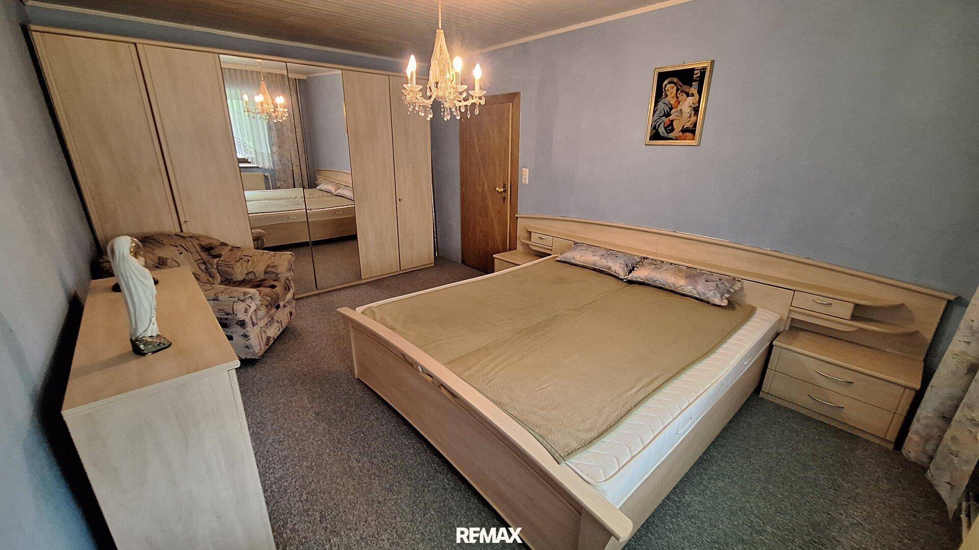 Geräumiges Schlafzimmer mit Doppelbett, Spiegelschrank und blauen Wänden.