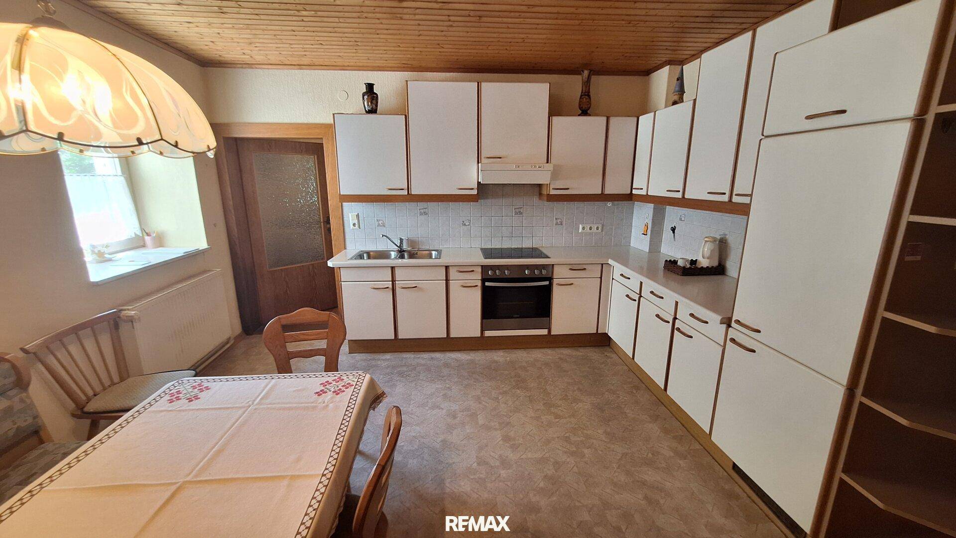 Helle Küche mit weißen Schränken, integriertem Backofen und Essbereich.