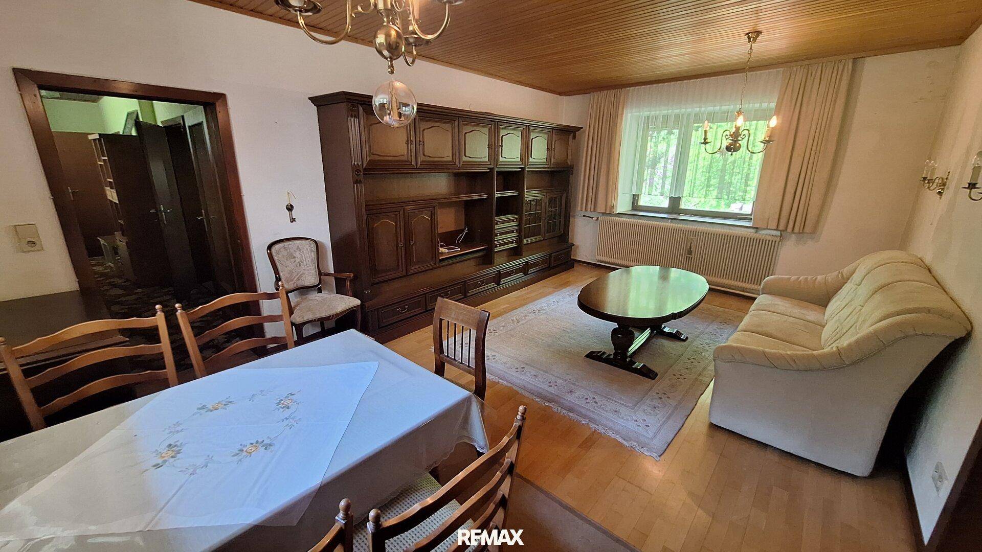 Kombinierter Wohn- und Essbereich mit Holzboden, großem Esstisch und Sofa.
