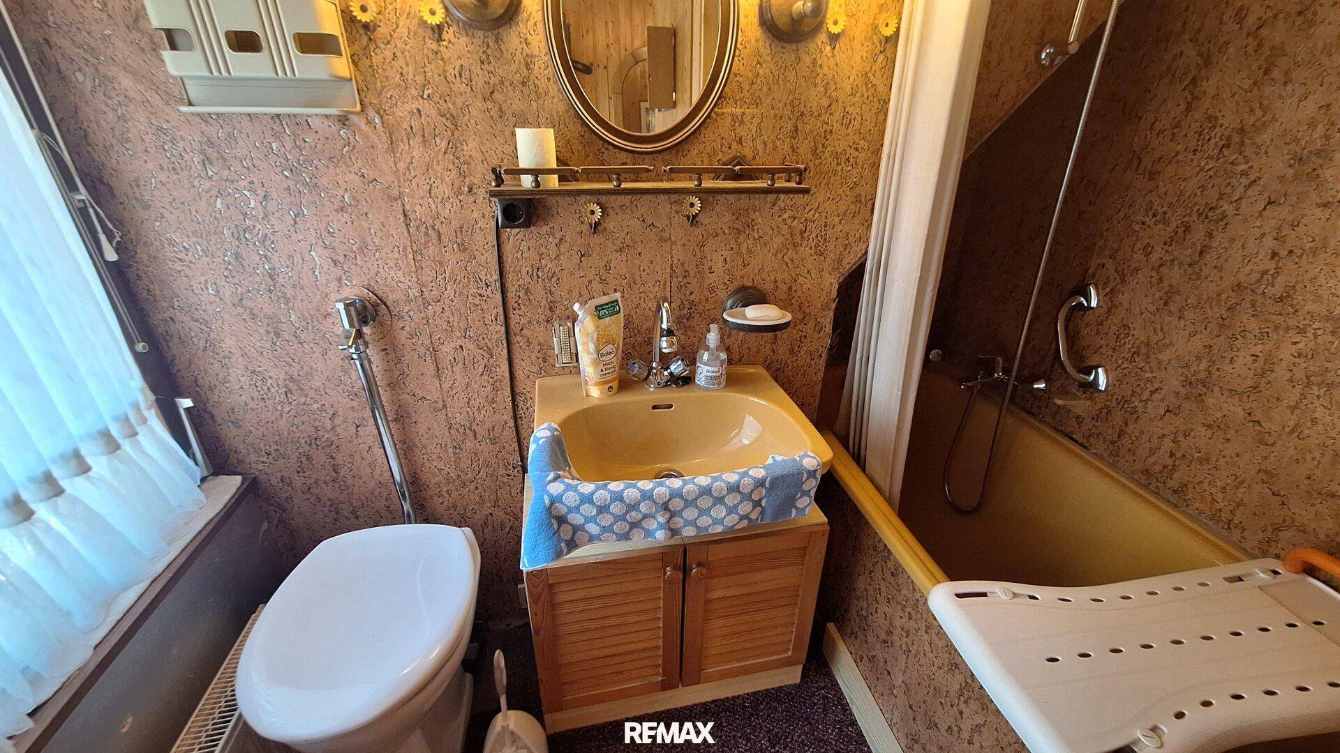 Badezimmer mit Badewanne, WC und gelbem Waschbecken, dekoriert mit rustikalen Elementen.