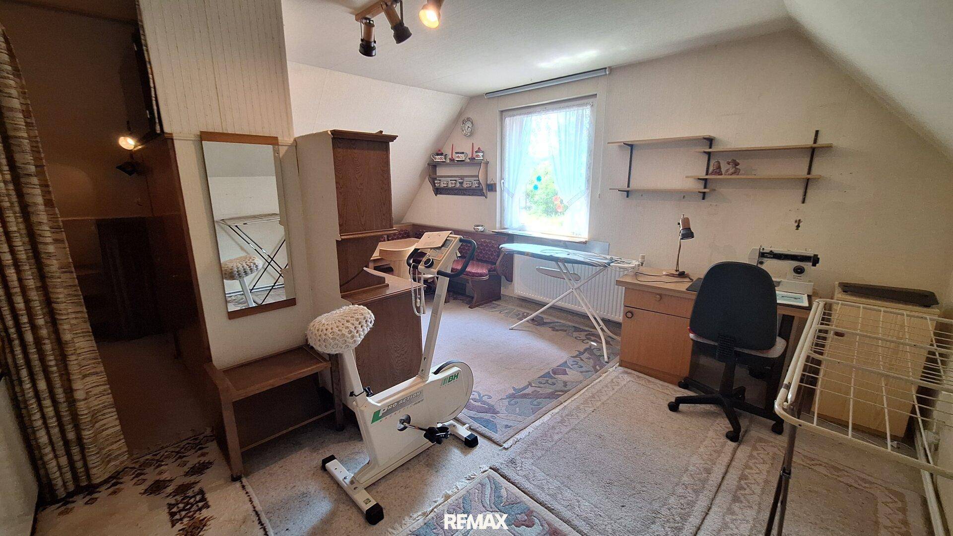 Dachgeschosszimmer als Büro oder Hobbyraum mit Fenster und Trainingsgerät.