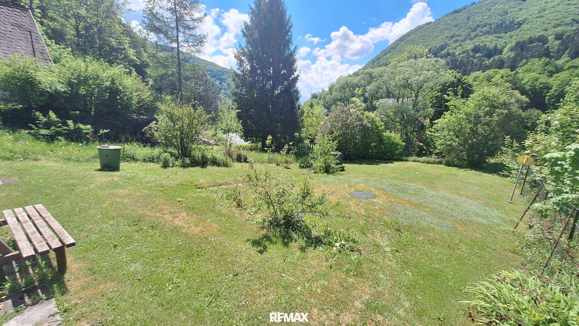 Großer, gepflegter Garten mit Rasenfläche, Bäumen und Bergblick im Hintergrund.