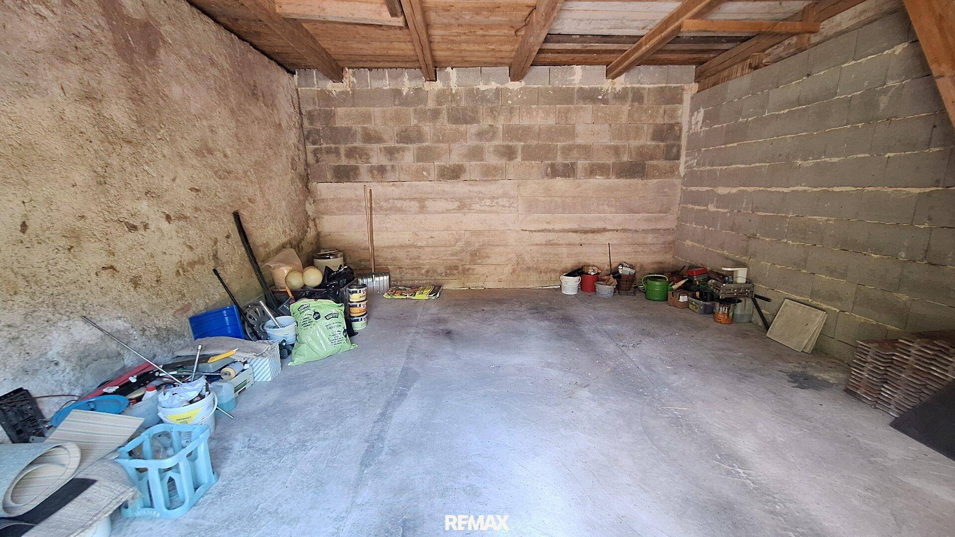 Großer, einfacher Lagerraum mit unverputzten Wänden und sichtbarer Holzbalkenkonstruktion.