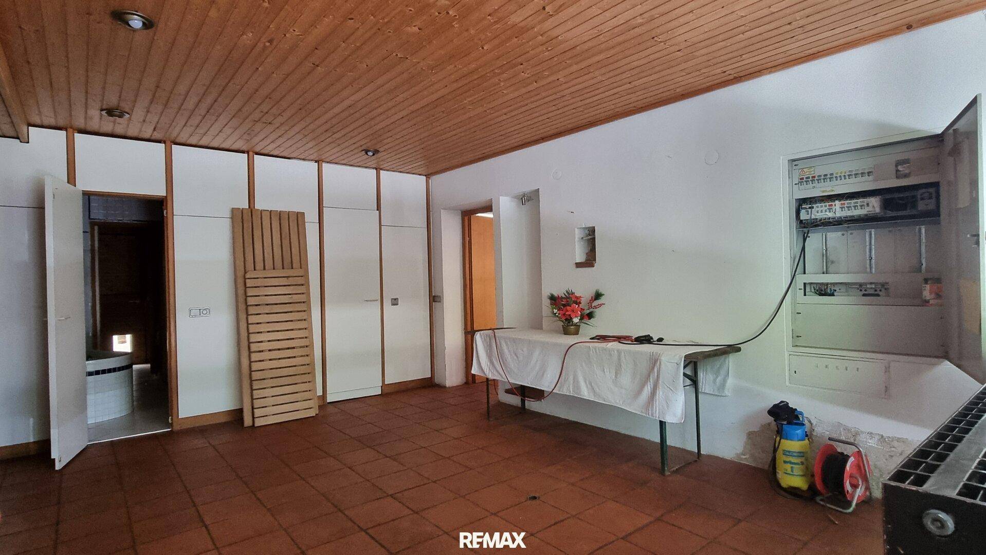 Praktischer Abstellraum mit Einbauschränken, Holzdecke und Zugang zu einem Badezimmer.