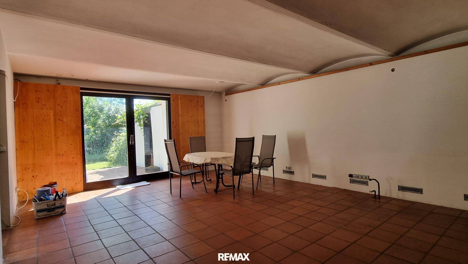 Essbereich mit Terrakottafliesen und großen Glastüren, die Zugang zum Garten bieten.