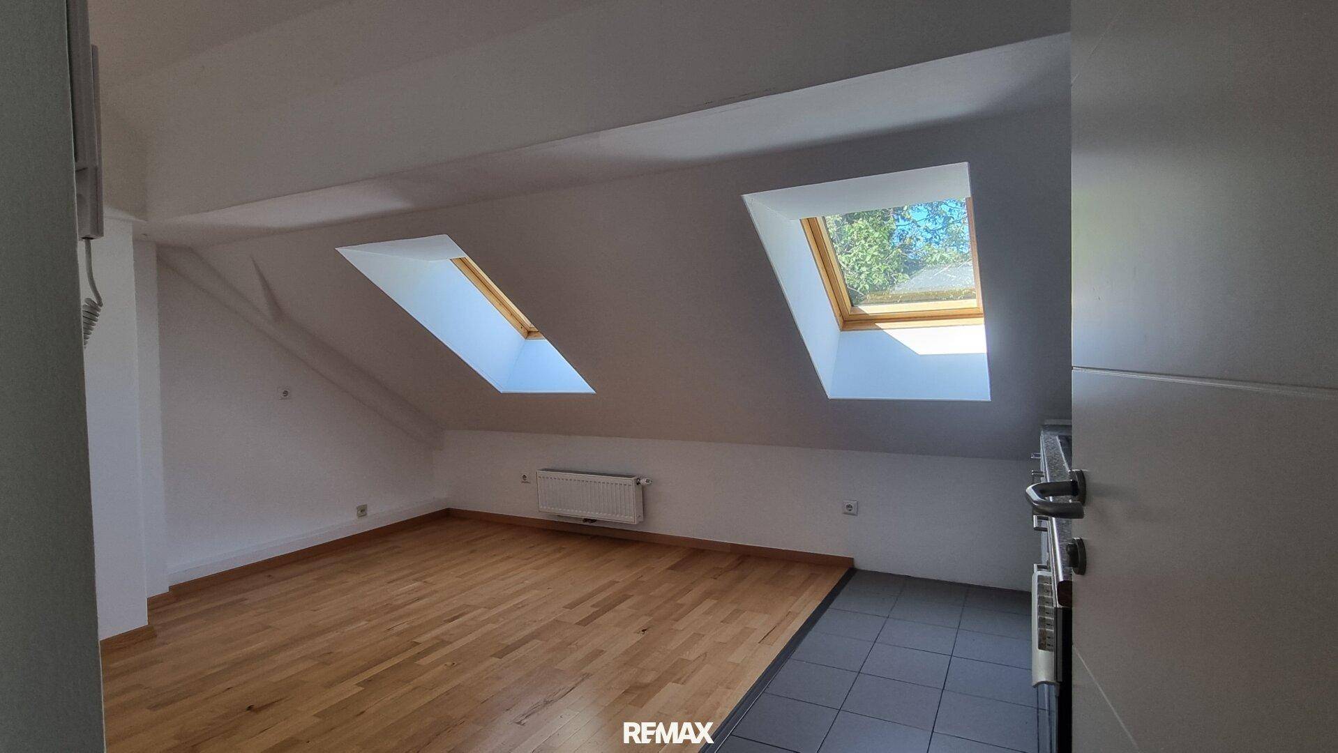 Geräumiges Dachgeschosszimmer mit Parkett- und Fliesenboden sowie zwei hellen Dachfenstern.