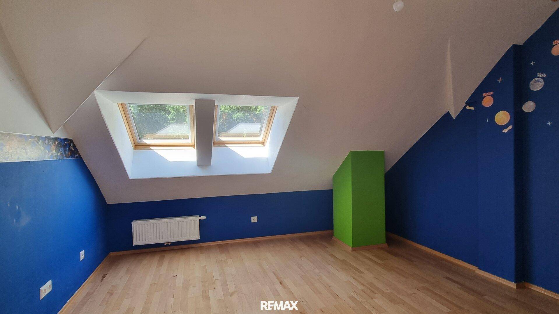Kinderzimmer mit blauen Wänden, Holzboden und Dachfenstern, ideal für Kinder.