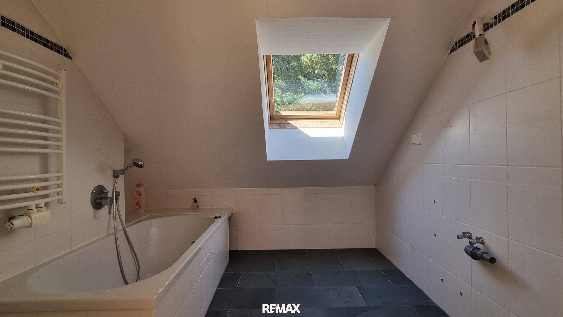 Badezimmer im Dachgeschoss mit Badewanne, Dachfenster und beheiztem Handtuchhalter.