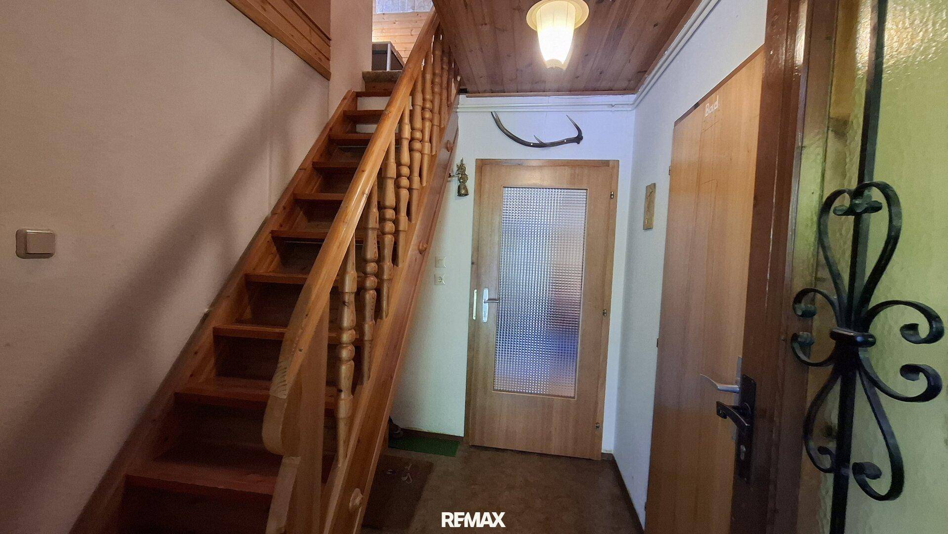 Heller Flur mit Holztreppe, die in die oberen Stockwerke führt.