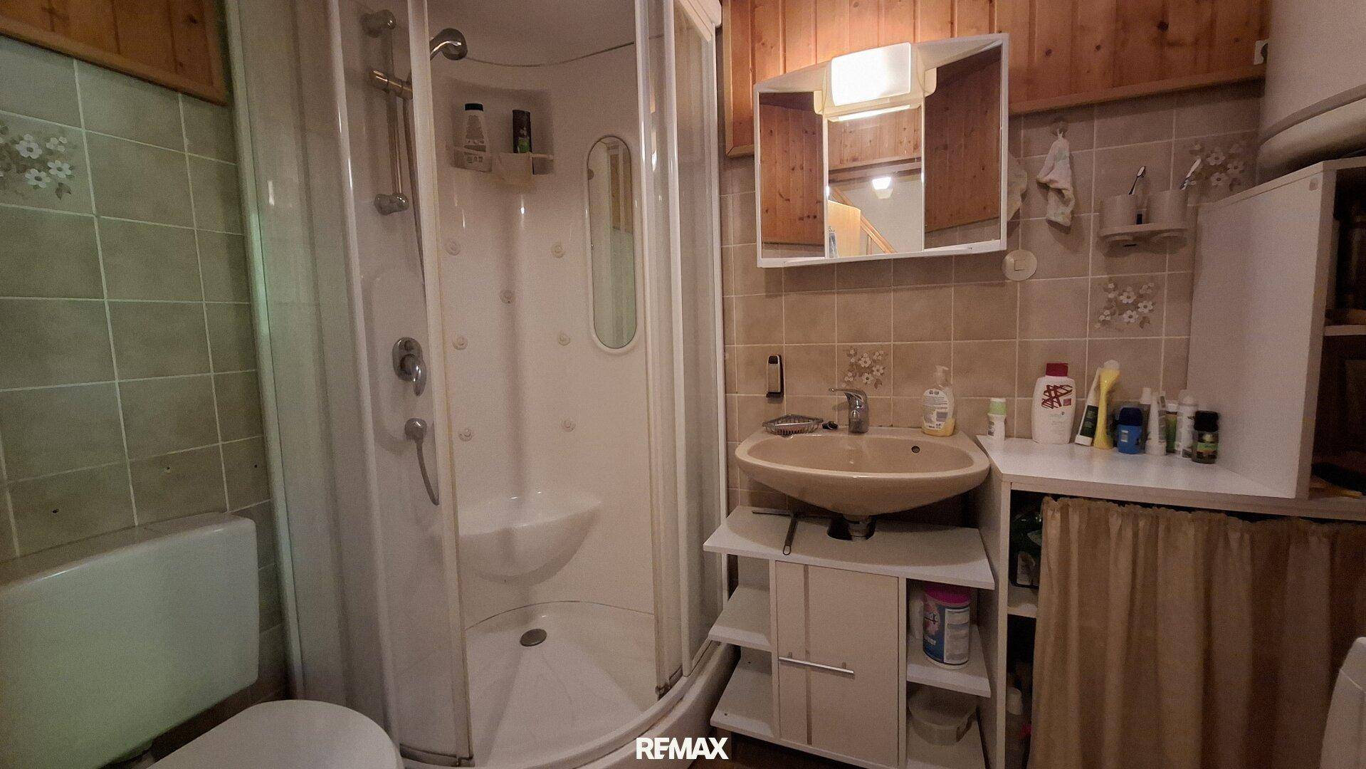 Badezimmer mit Duschkabine, Waschbecken und Fliesen im traditionellen Stil.