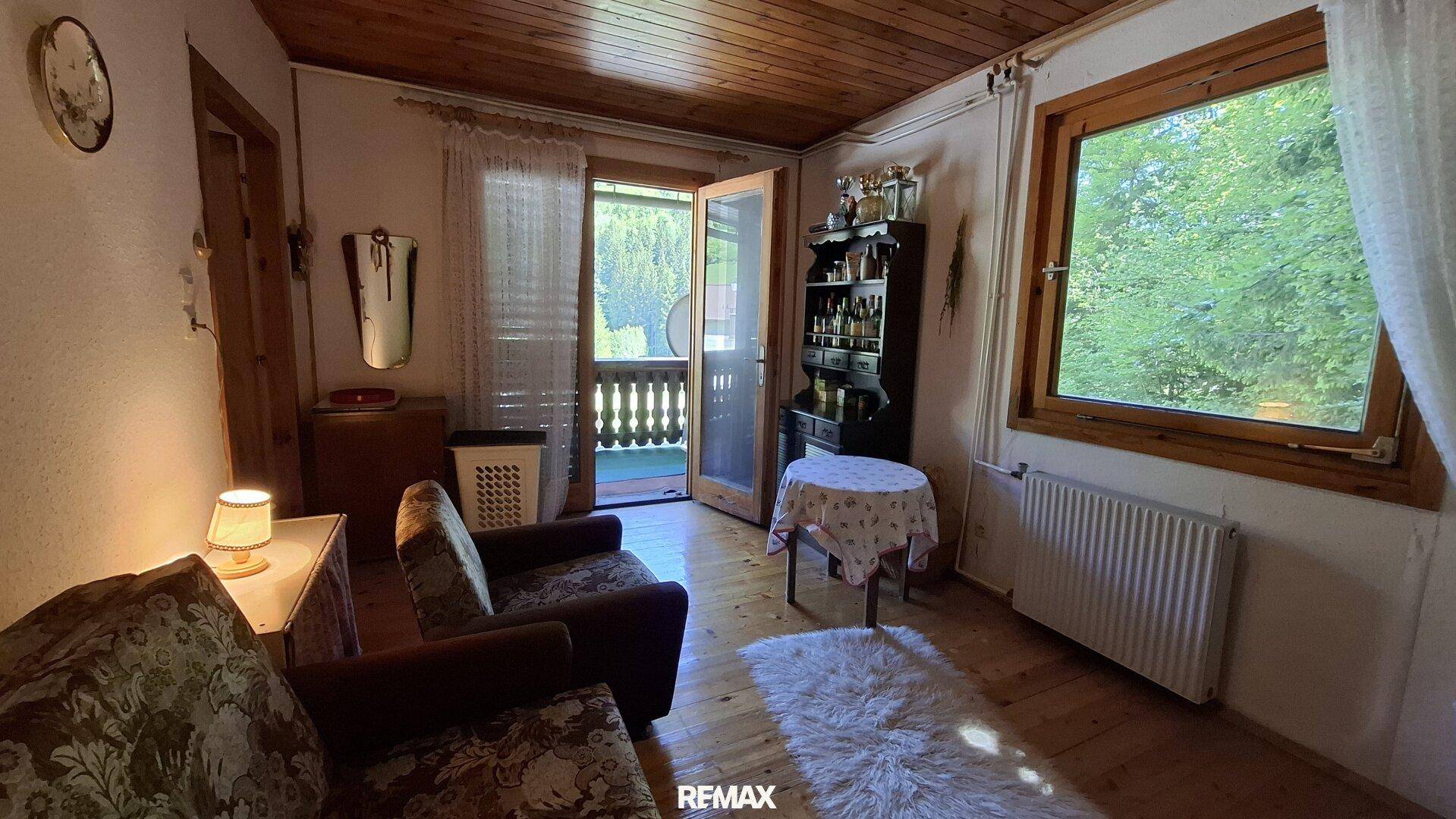 Wohnzimmer mit gemütlichen Sesseln, Holzboden und Zugang zum Balkon.
