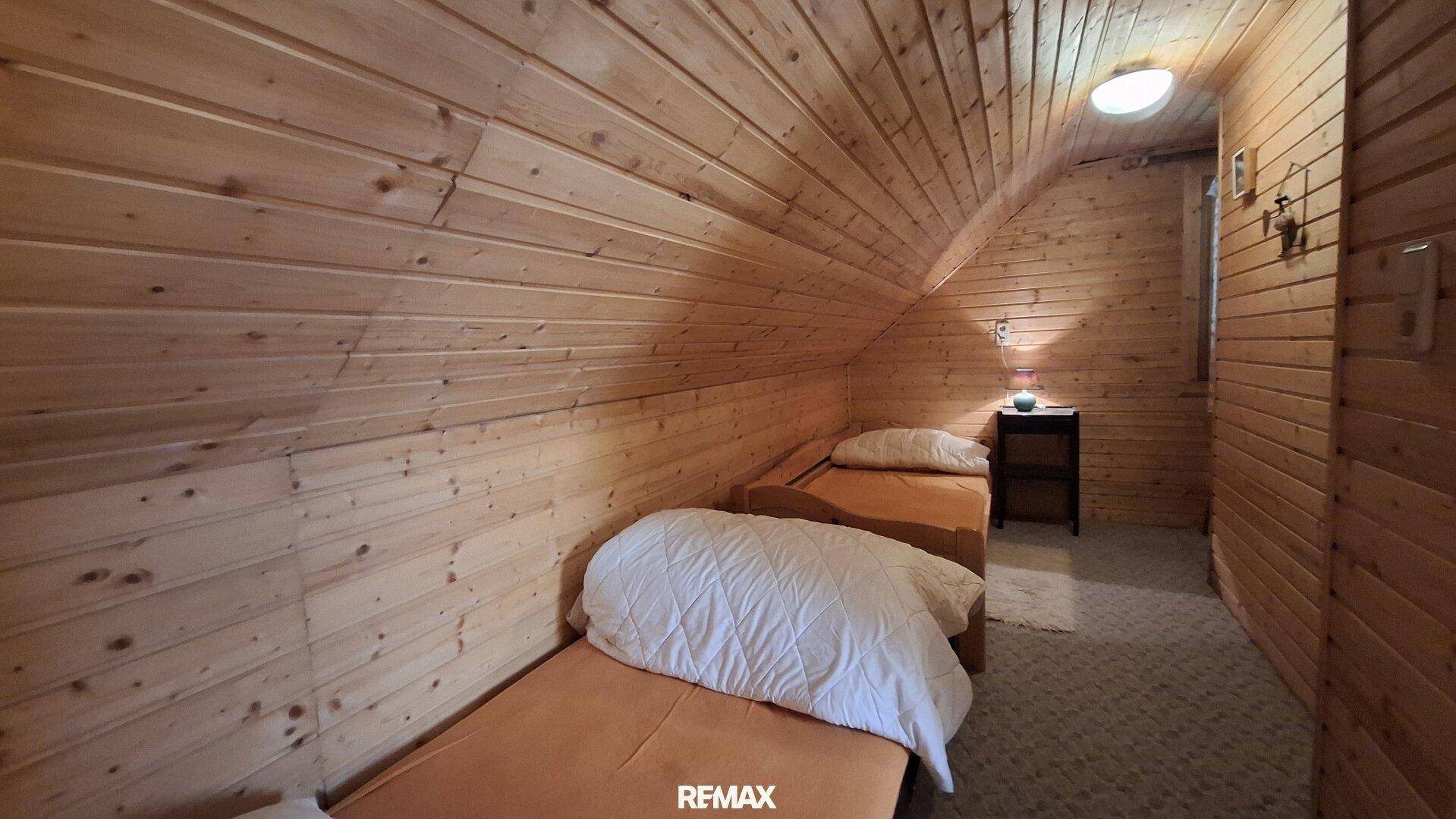 Kleines Schlafzimmer mit zwei Einzelbetten, Holztäfelung und Dachschräge.
