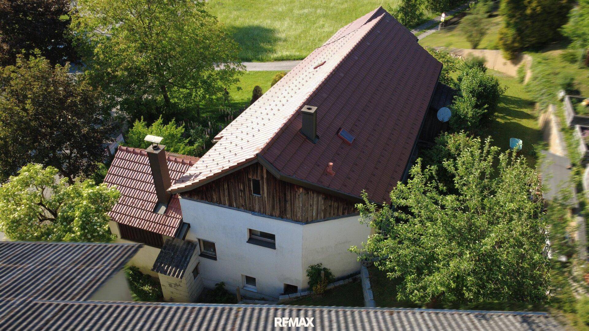 Luftaufnahme des Hauses mit rotem Ziegeldach und umgebenden Bäumen.