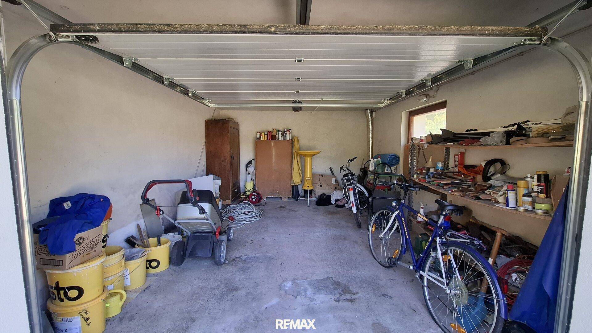 Garage als Abstellraum mit Werkzeugen, Fahrrädern und verschiedenen Lagergegenständen.