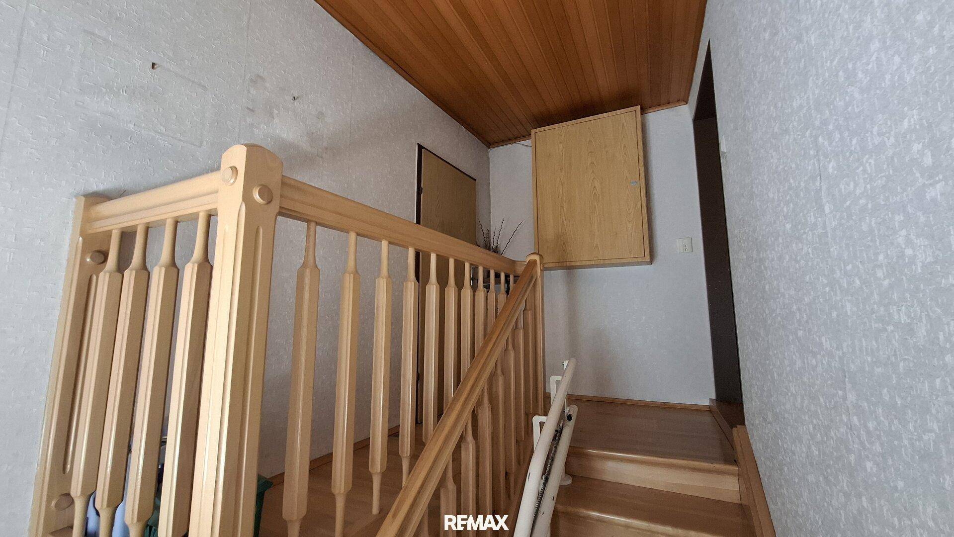 Holztreppe führt in das obere Stockwerk, umgeben von Holzverkleidungen.