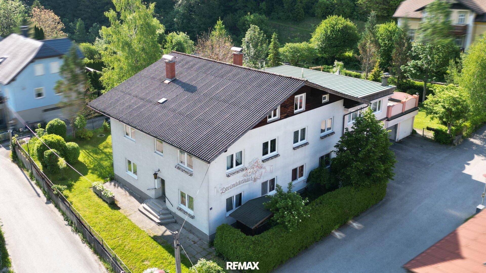 Luftaufnahme des Anwesens mit umliegender grüner Landschaft und Nachbargebäuden.