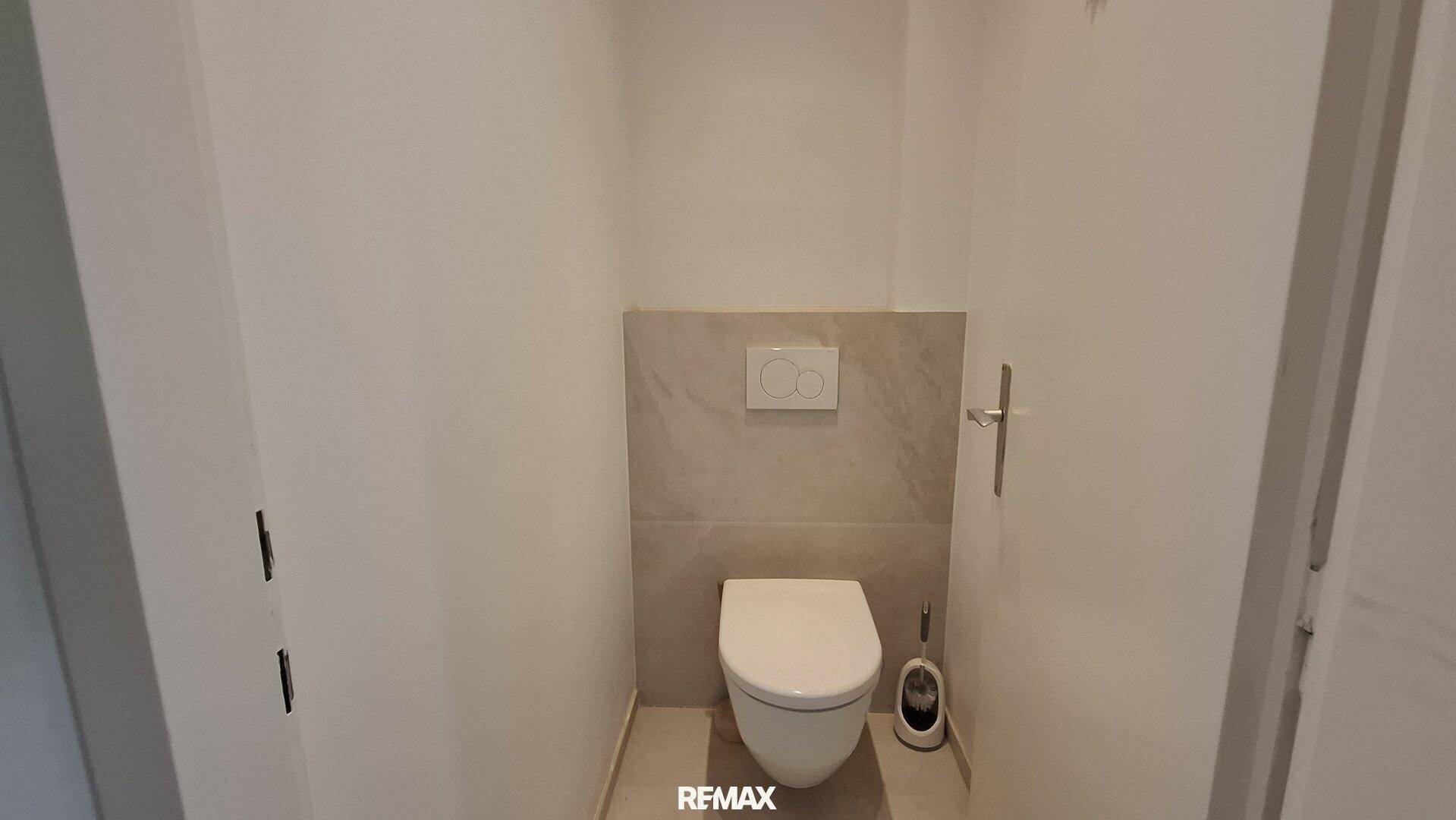 Modernes Gäste-WC mit wandhängender Toilette und hellen Fliesen.
