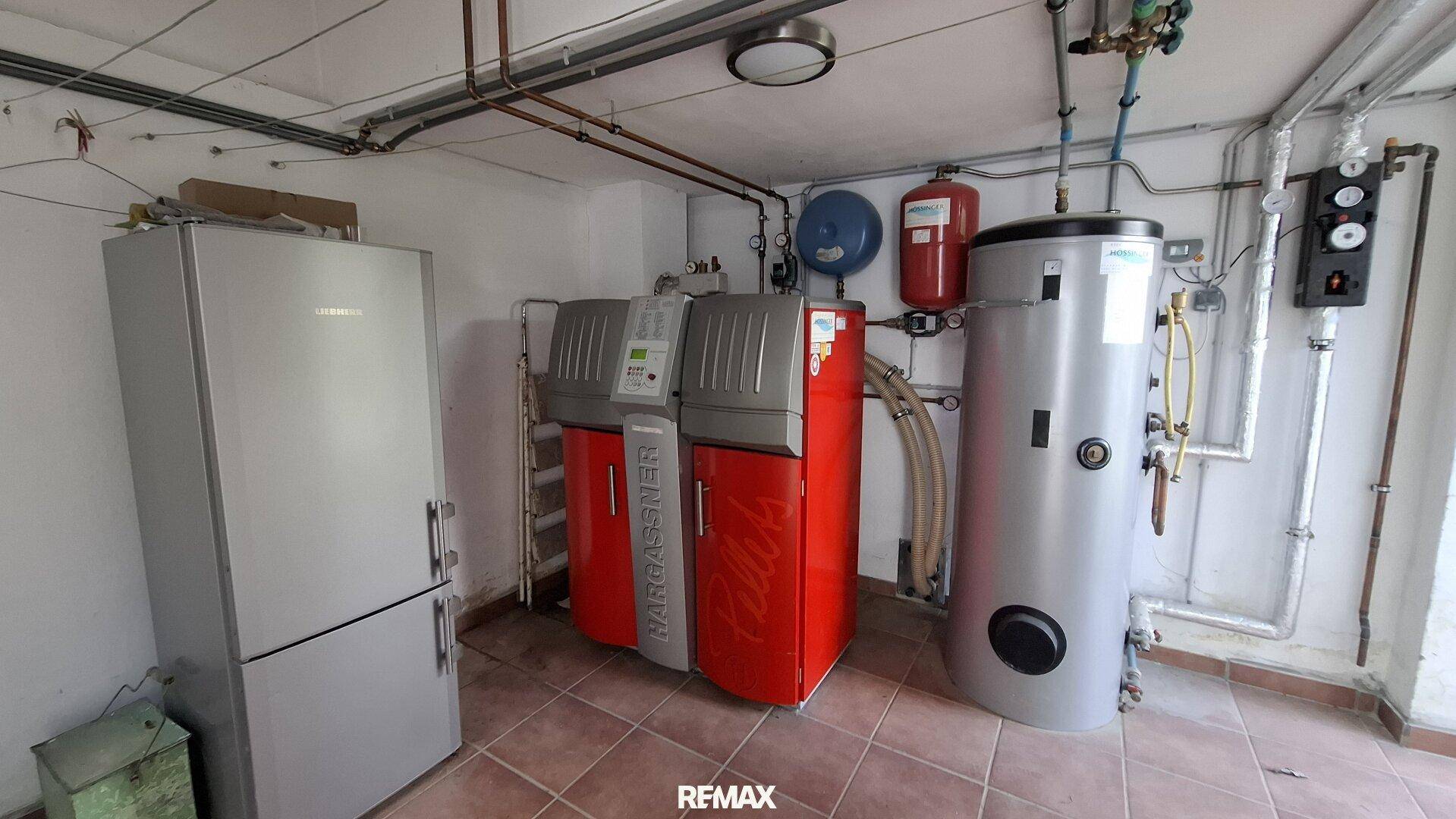 Heizungsraum mit moderner Pelletheizung, Warmwasserspeicher und Kühlschrank.