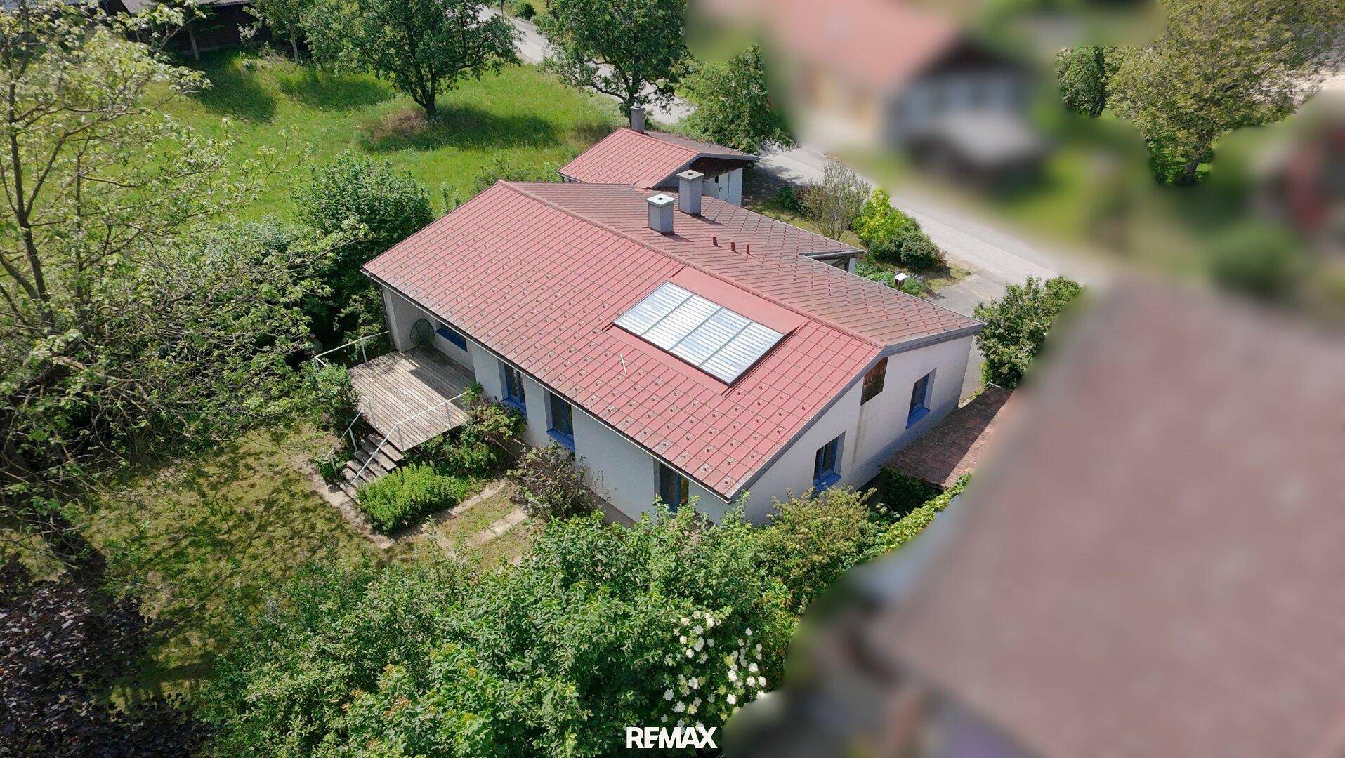 Luftaufnahme des Hauses mit rotem Dach, Solaranlage und umgebender Natur.