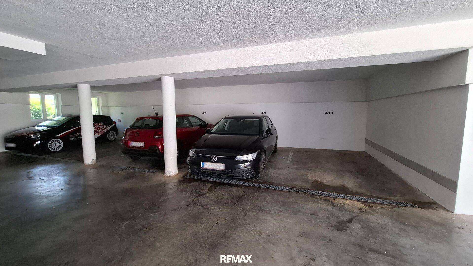 Tiefgarage mit mehreren Stellplätzen und geparkten Fahrzeugen, bietet sicheren Unterstand.