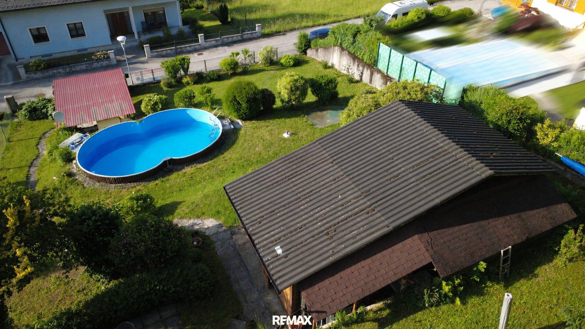 Übersicht des Grundstücks mit Pool, Garten und angrenzendem Waldgebiet.