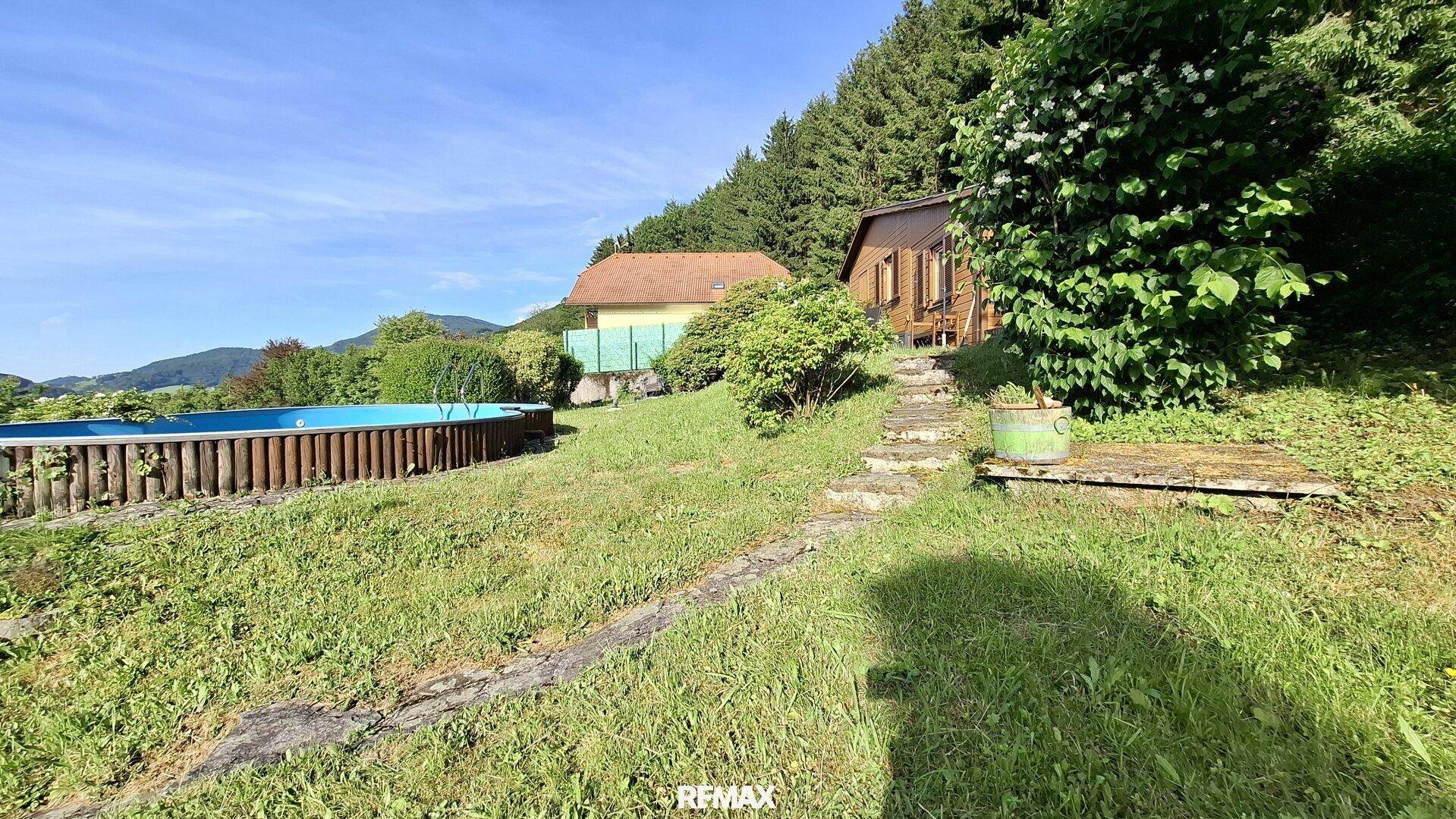 Hanglage des Grundstücks mit Pool, umgeben von üppiger Vegetation und Bäumen.