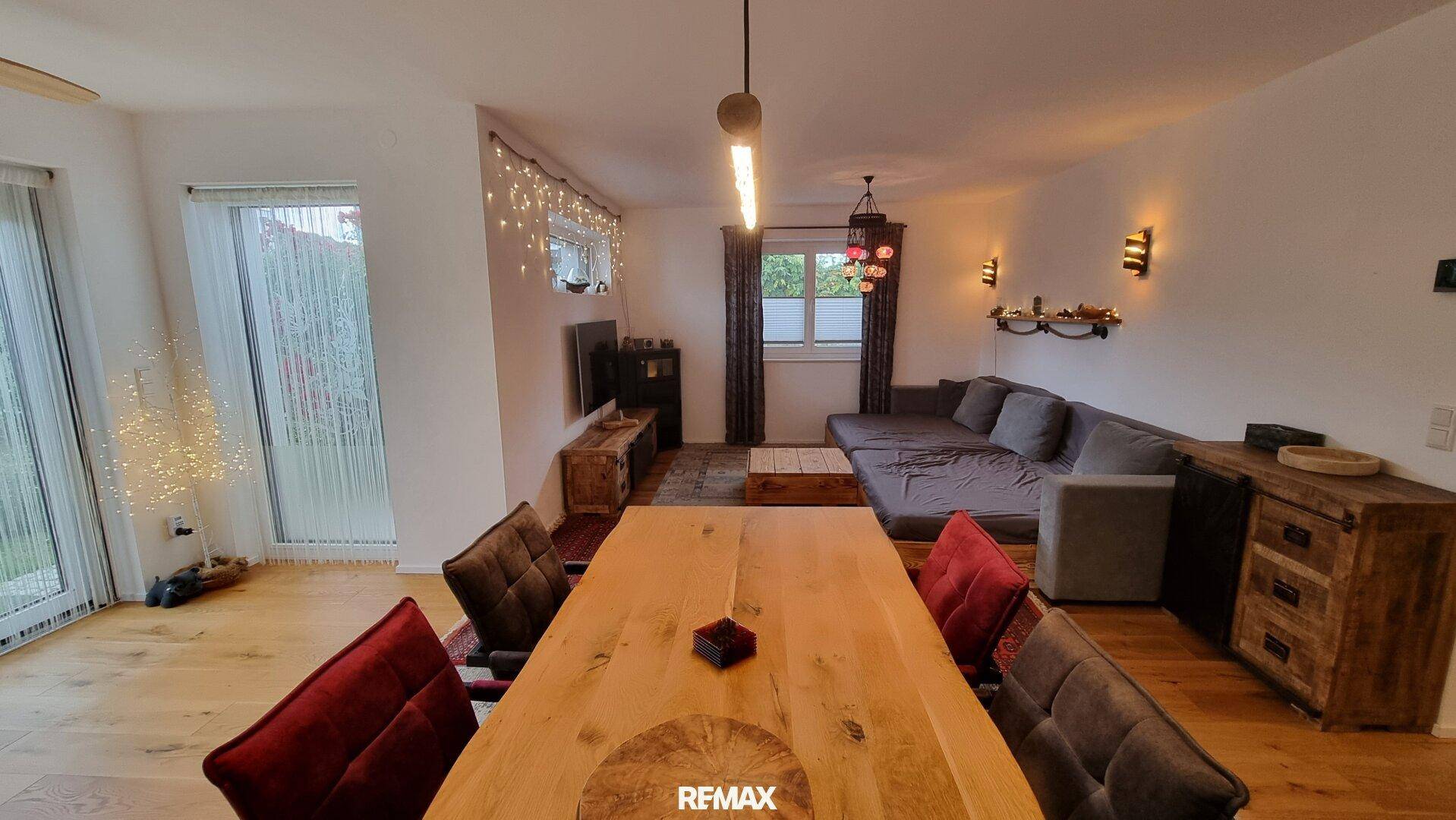 Heller Wohn-Essbereich mit großem Holztisch, gemütlicher Sitzecke und Zugang zum Garten.