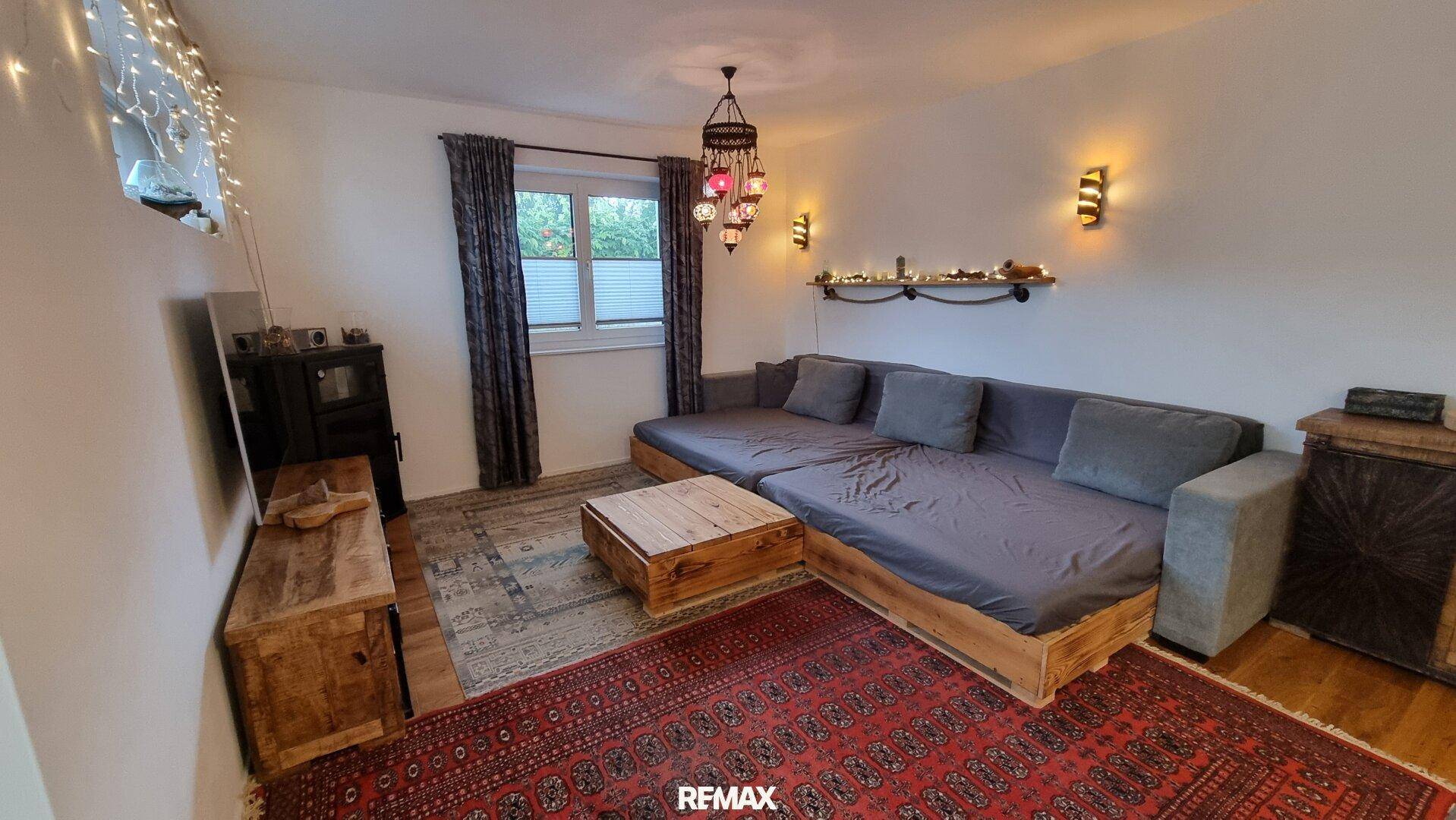 Gemütlicher Wohnbereich mit bequemer Couch, Teppich und stimmungsvoller Beleuchtung.