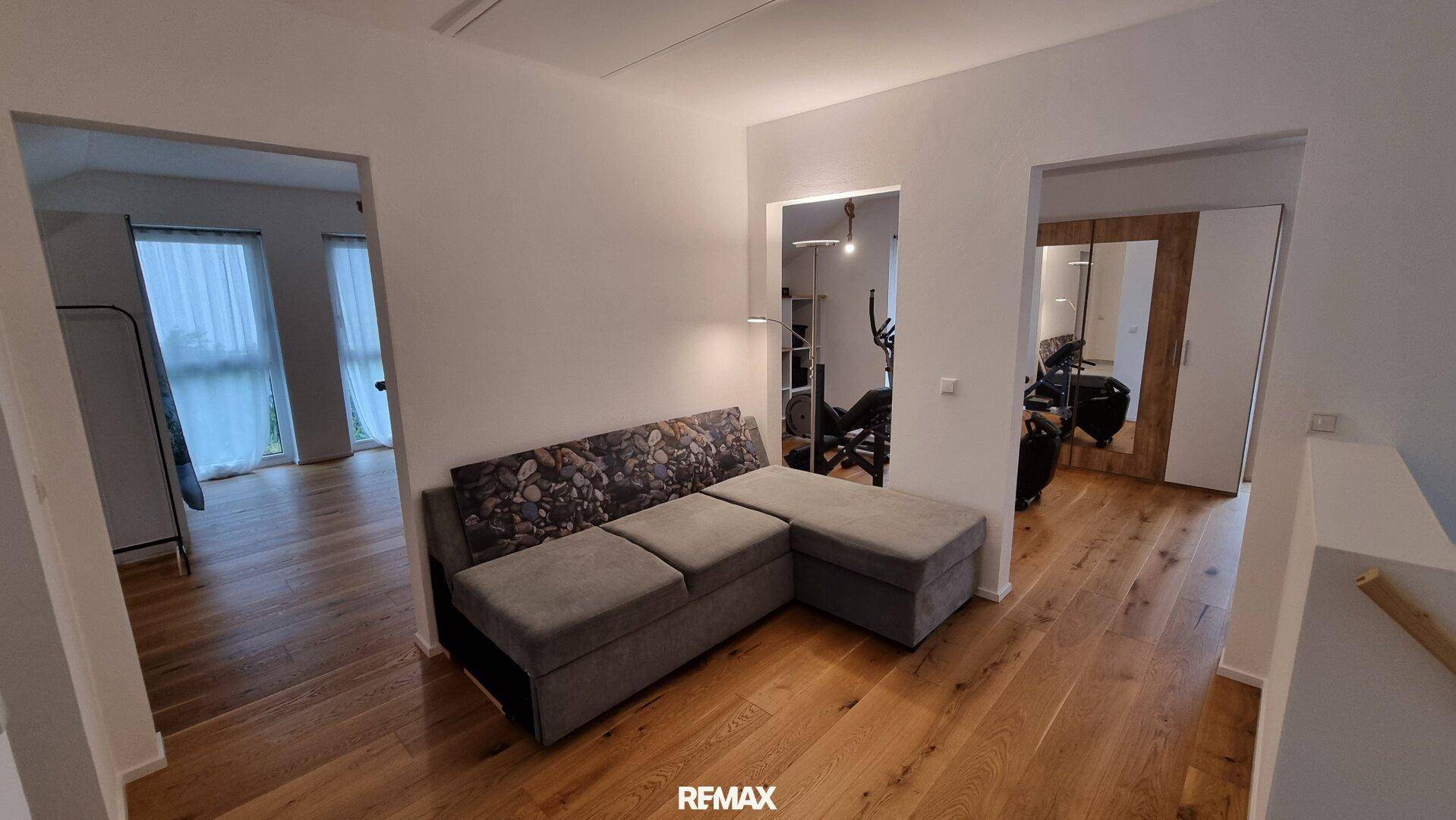 Heller Flurbereich im Obergeschoss mit Sofa und Blick in angrenzende Zimmer.