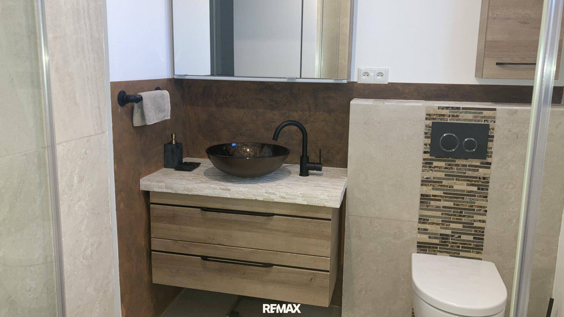 Modernes Badezimmer mit stilvollem Waschbecken, Wand-WC und eleganten Fliesen.