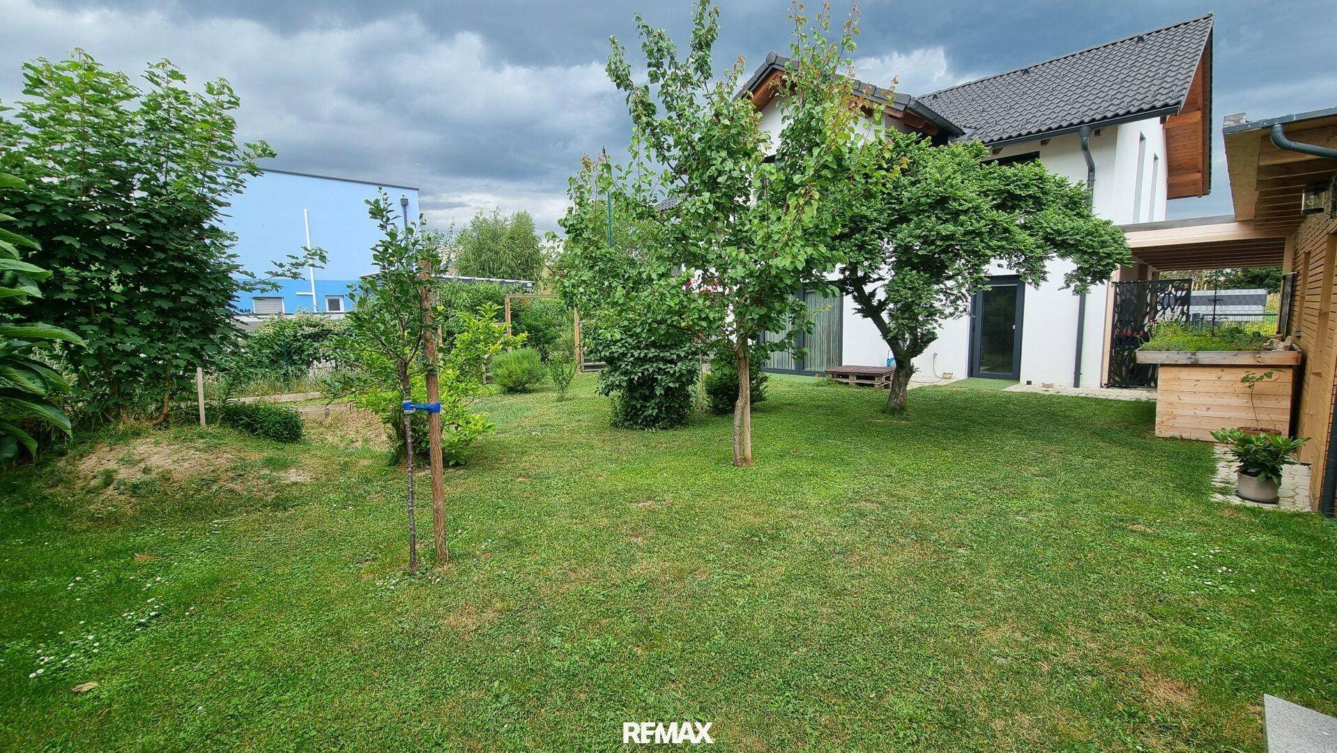 Großer Garten mit viel Grün, Bäumen und einem Blick auf die Rückseite des Hauses.