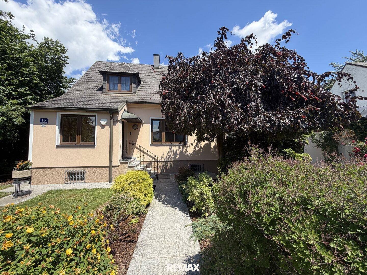 Vorderansicht des Hauses mit gepflegtem Vorgarten und blühenden Pflanzen.