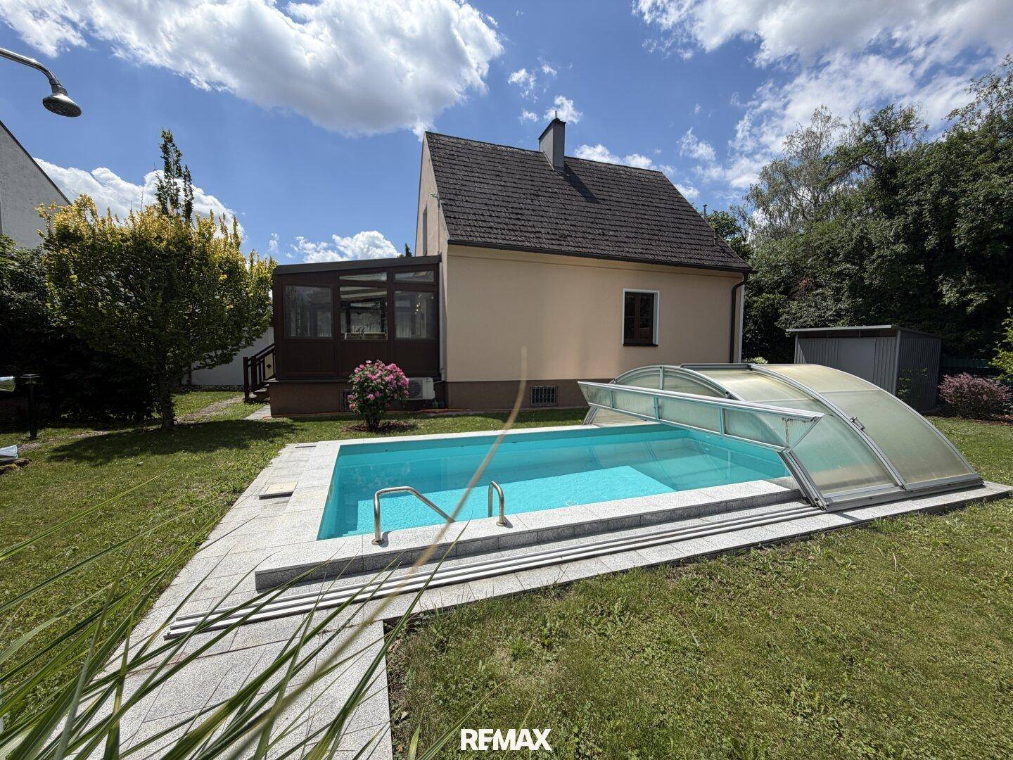 Rückansicht des Hauses mit Pool im Garten unter blauem Himmel.