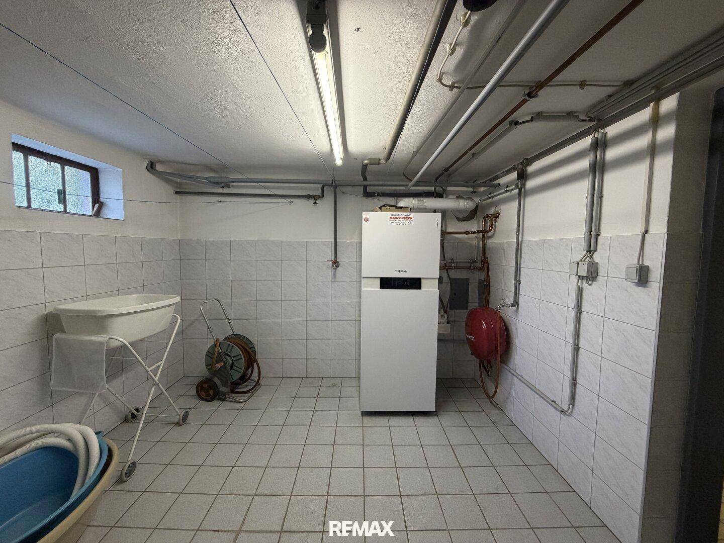 Heizungsraum im Keller mit modernem Heizsystem und gefliestem Boden.