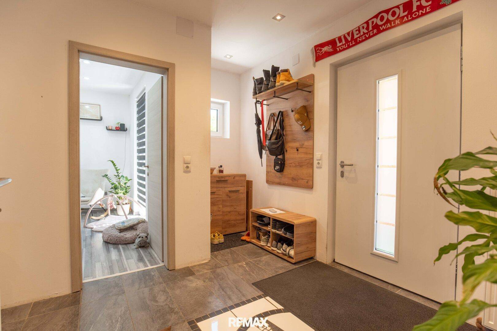 Heller Eingangsbereich mit Fliesenboden, Garderobe und Zugang zu weiteren Räumen.