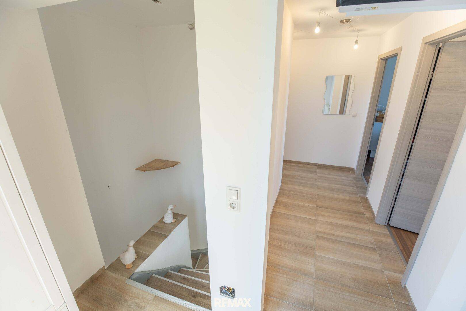 Heller Treppenaufgang mit Holzstufen und modernem Geländer.