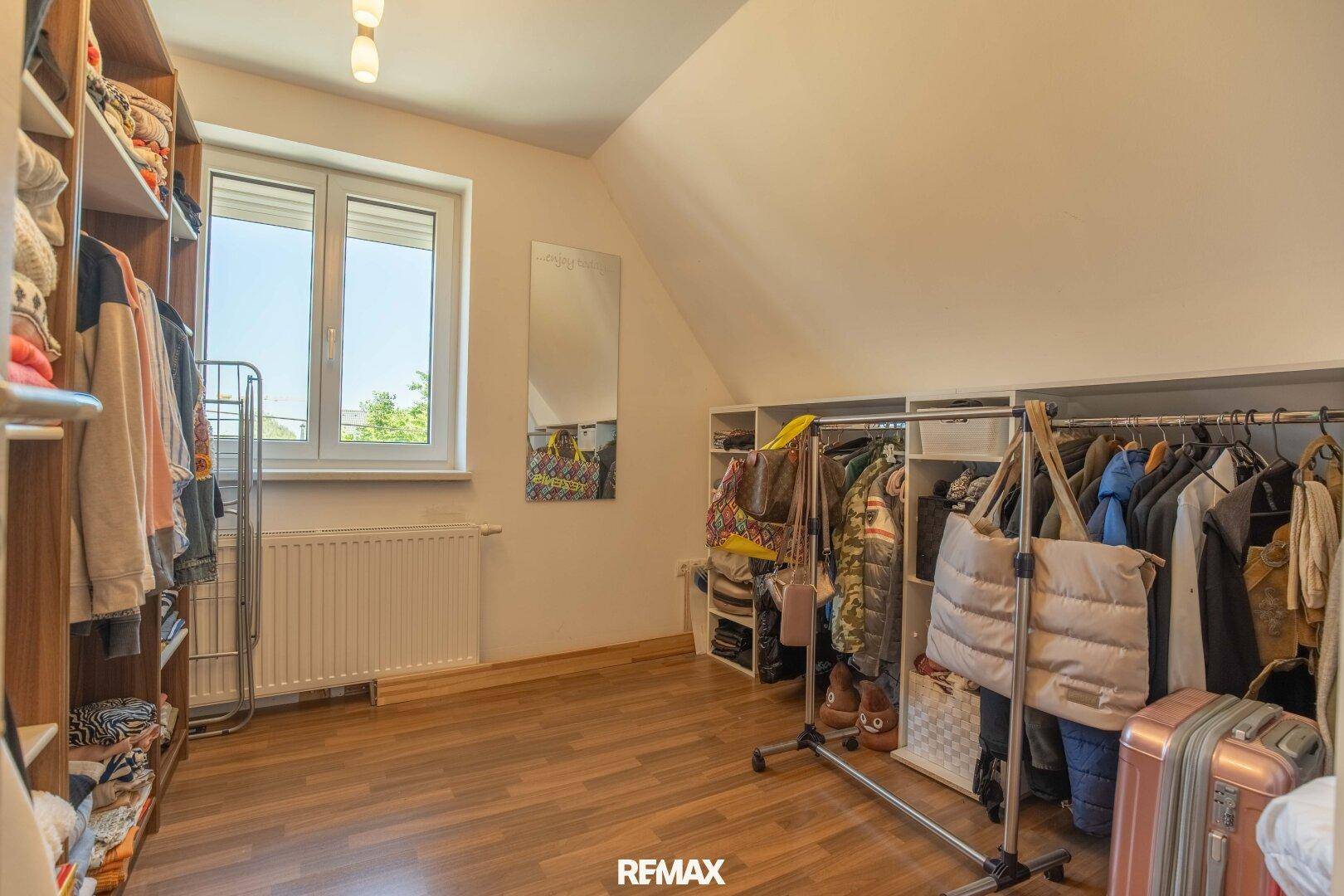 Geräumiger begehbarer Kleiderschrank mit viel Stauraum und Fenster.