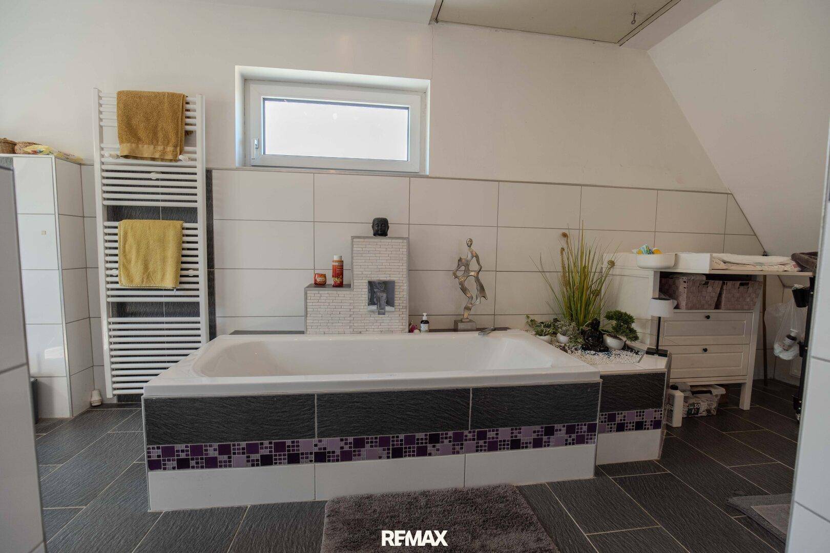Badezimmer mit Badewanne, beheiztem Handtuchhalter und Fenster.