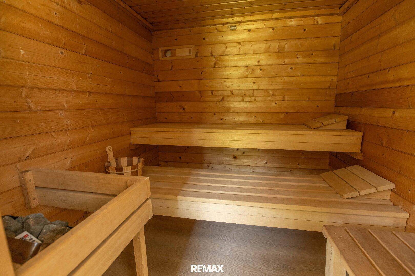 Holzvertäfelte Sauna mit Bänken und traditionellem Saunaofen.