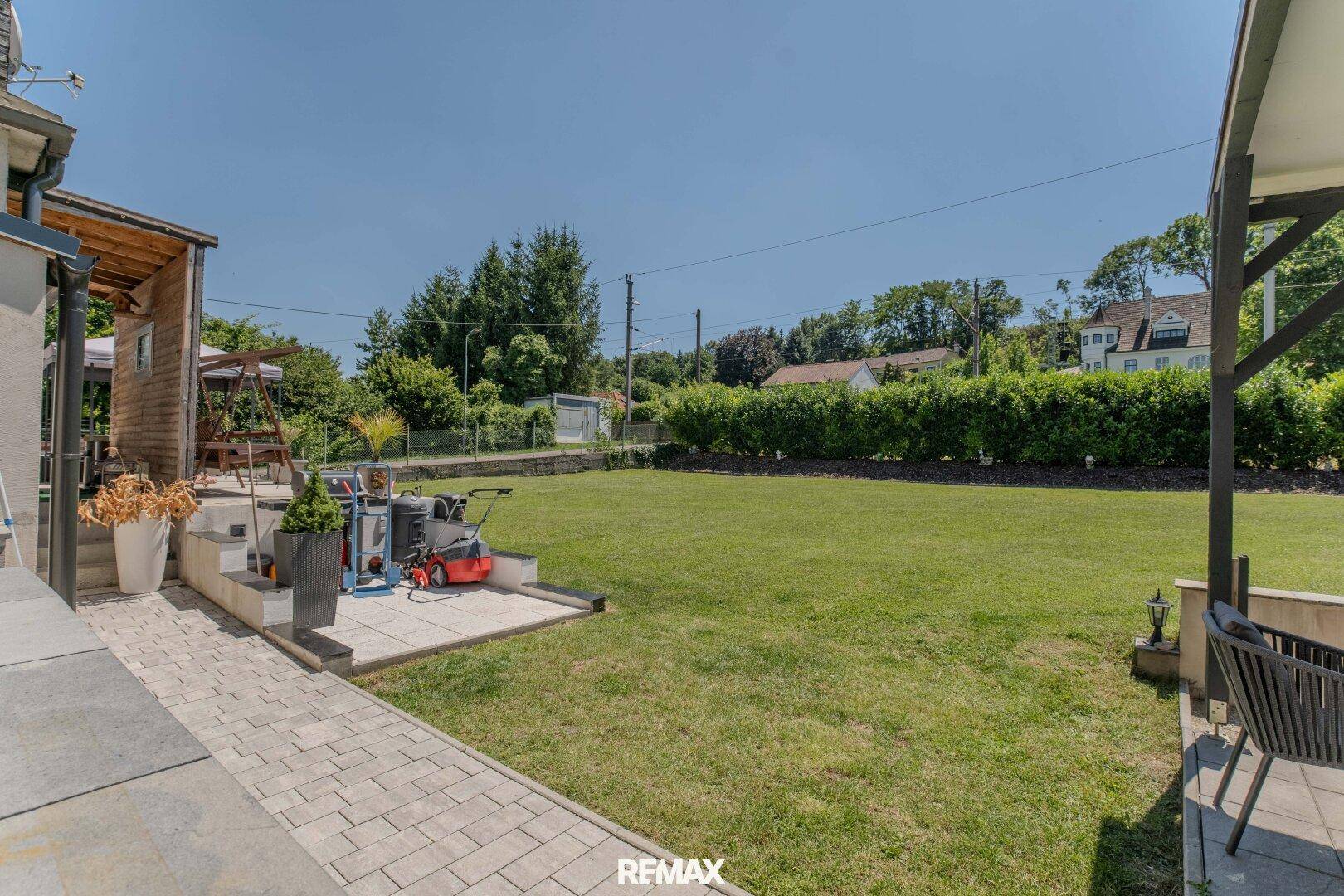 Großer, gepflegter Garten mit Rasenfläche und gepflastertem Weg, ideal für Entspannung im Freien.
