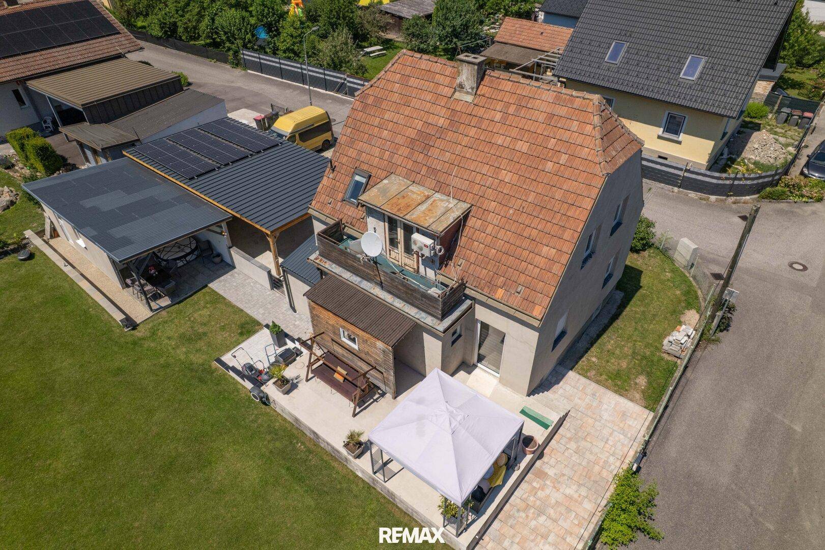Vogelperspektive des Hauses mit Ziegeldach, Balkon, Terrasse und angrenzendem Gartenbereich.